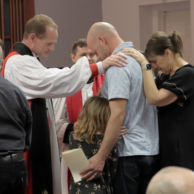 Church members praying over a man getting confirmed